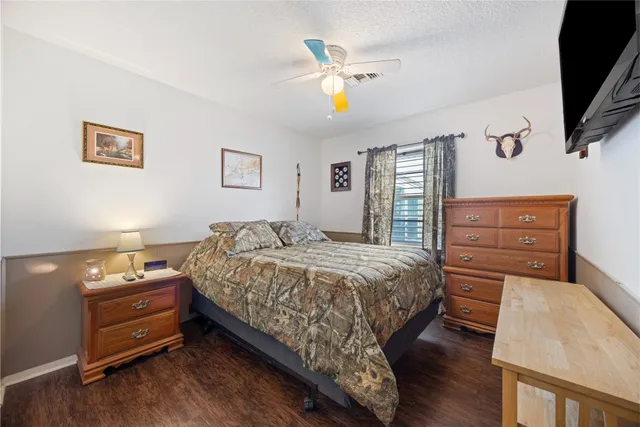 a bedroom with a bed and a flat tv screen on dresser