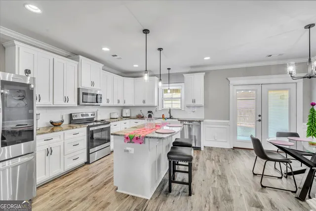 a kitchen that has a lot of white cabinets and wooden floor