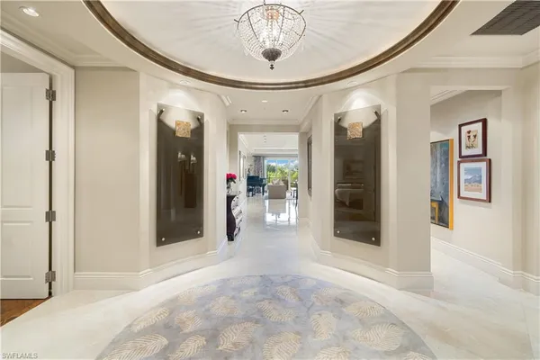 a view of a hallway with wooden floor and a chandelier