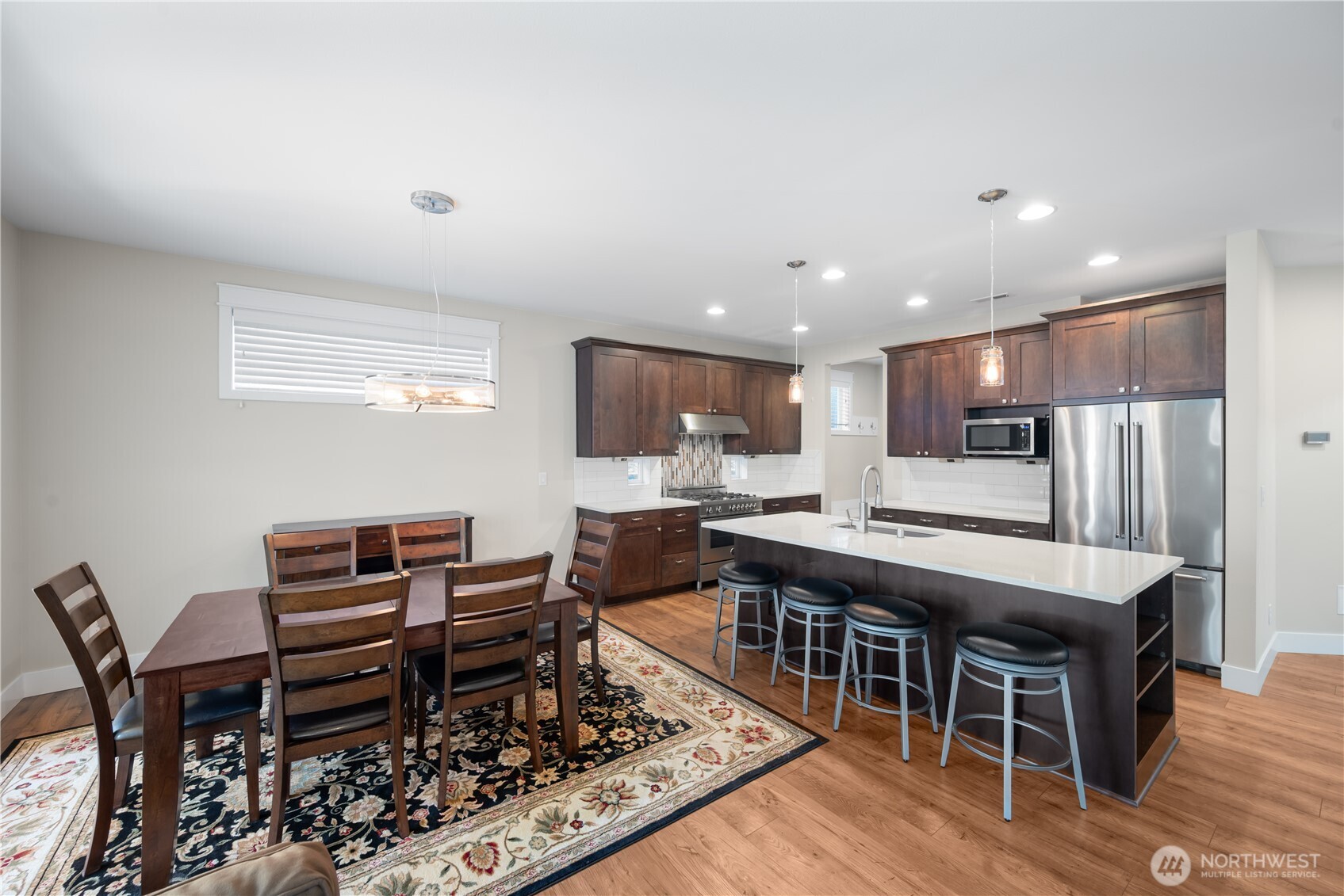 26925 230th Place Southeast Maple Valley, WA 98038 - Photo 3 of 32 a kitchen with stainless steel appliances kitchen island granite countertop a table chairs and a refrigerator