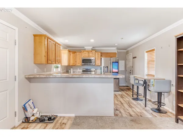 a kitchen with stainless steel appliances granite countertop a refrigerator a sink dishwasher a stove and a dining table with wooden floor