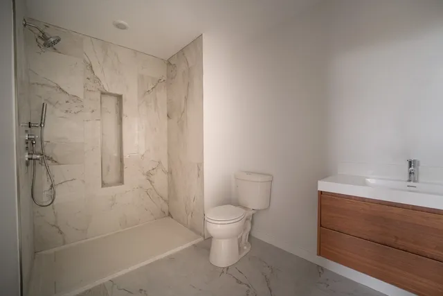 a bathroom with a granite countertop sink a toilet and shower