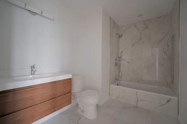 a bathroom with a granite countertop sink a toilet and shower