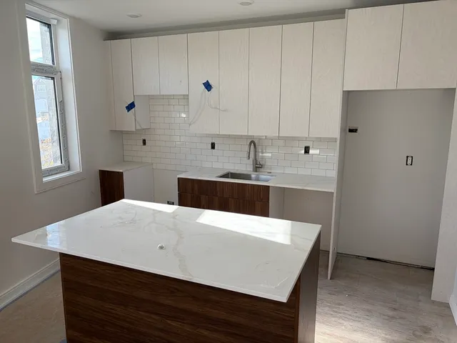 a kitchen with stainless steel appliances a white table chairs and a refrigerator