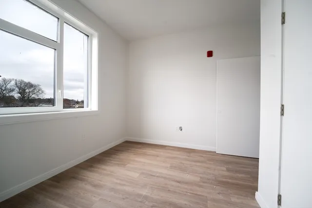 a view of an empty room with wooden floor and windows