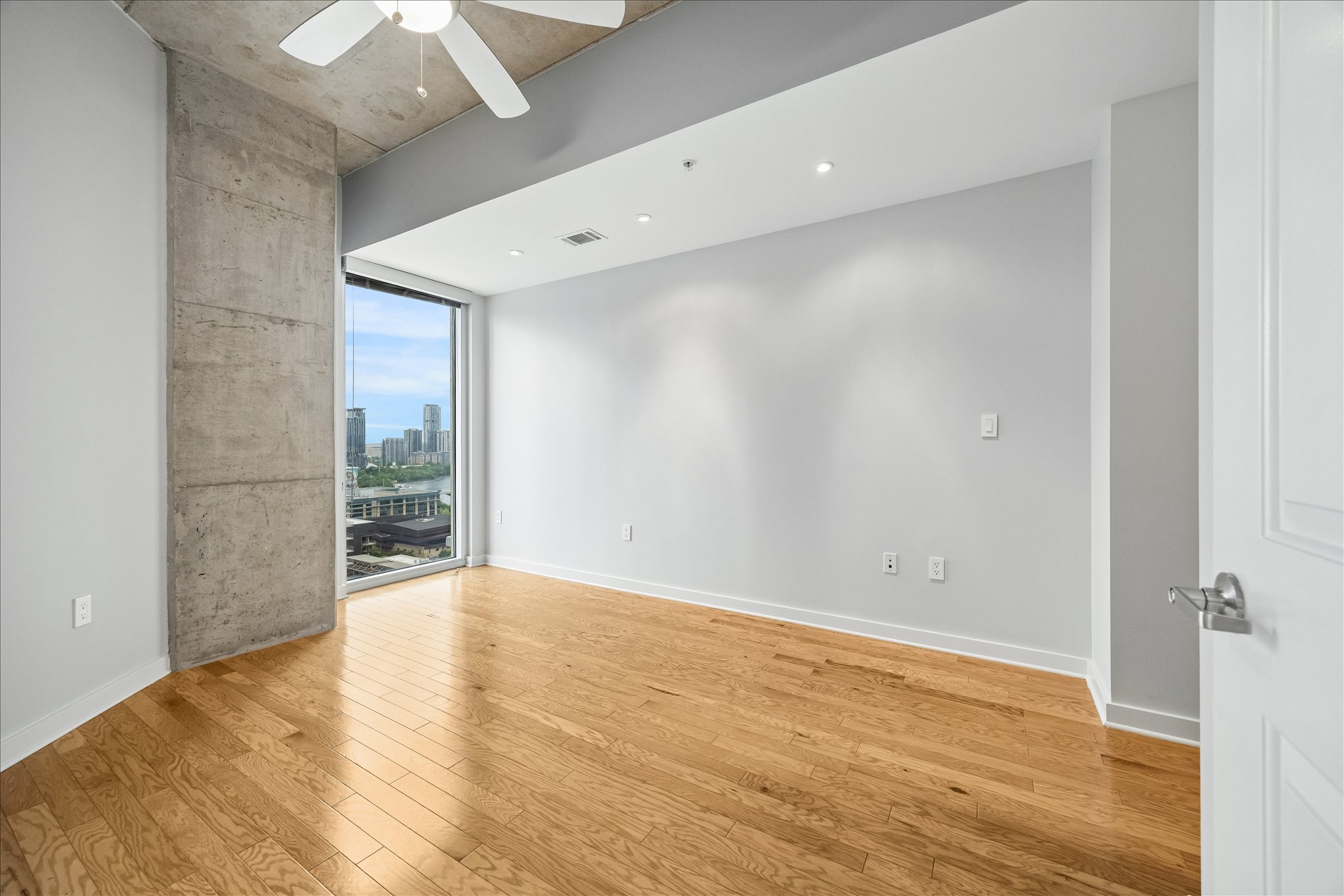 360 Nueces Street, Unit 2005 Austin, TX 78701 - Photo 12 of 35 This space features hardwood floors, a concrete accent wall, and a large window providing city views