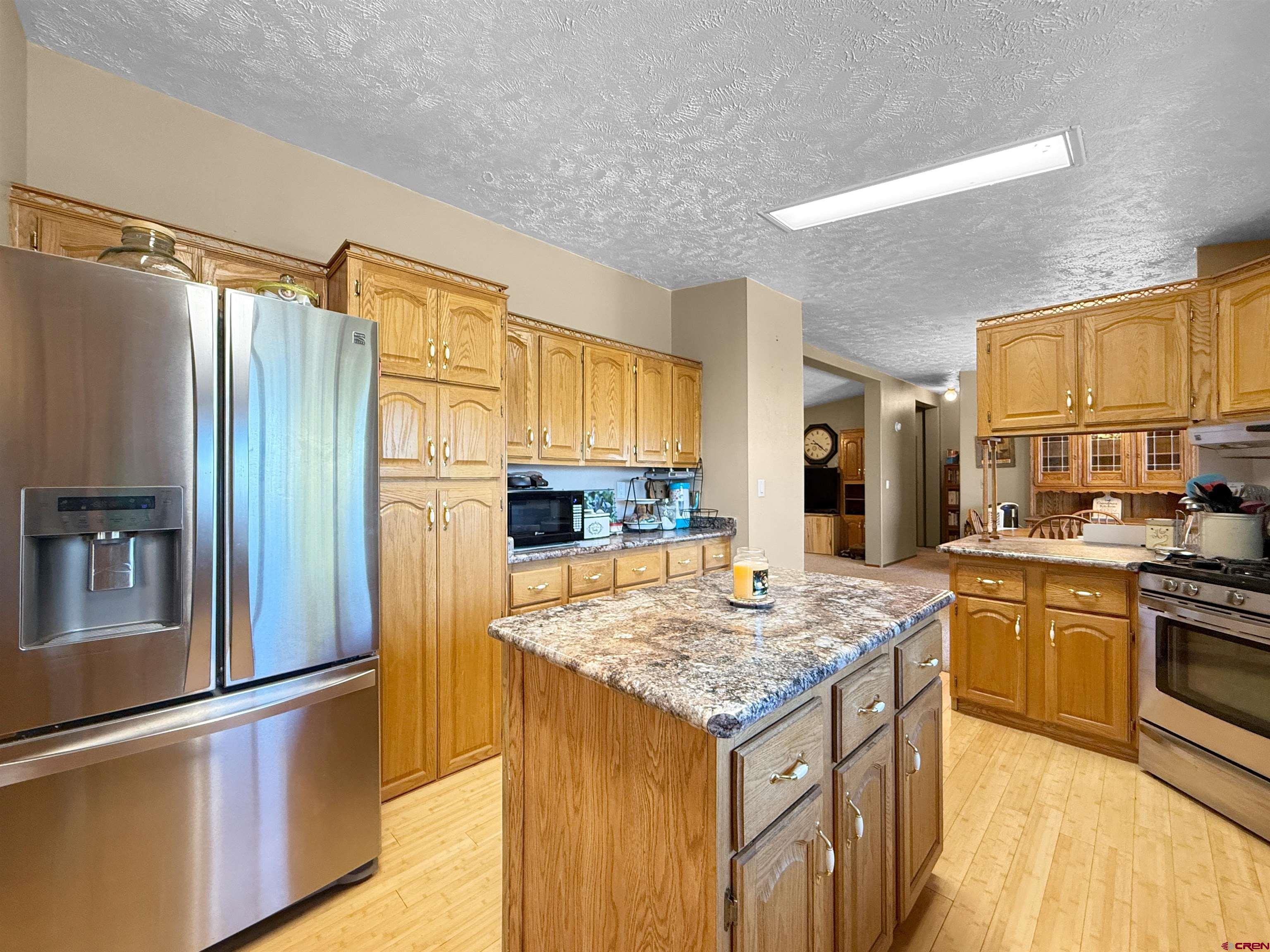 18311 2550th Road Cedaredge, CO 81413 - Photo 6 of 29 a kitchen with granite countertop kitchen island wooden cabinets a refrigerator stove and a sink