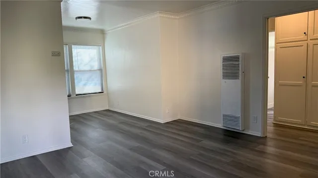 an empty room with wooden floor and cabinet