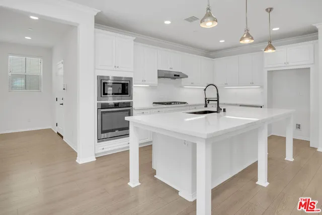 a kitchen with kitchen island a sink stainless steel appliances and cabinets