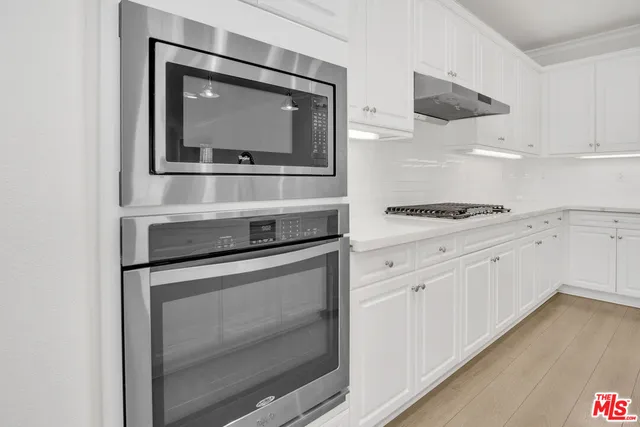 a kitchen with white cabinets and appliances