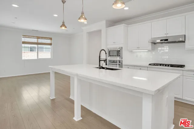 a kitchen with kitchen island white cabinets and wooden floor