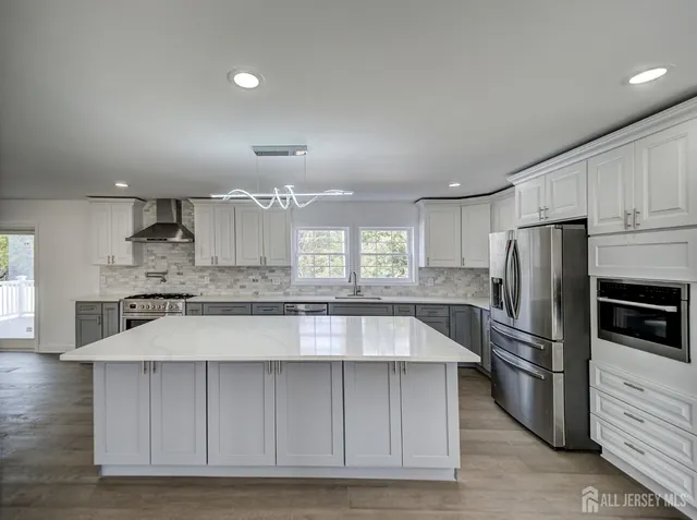 a kitchen with stainless steel appliances granite countertop a stove a sink a refrigerator and white cabinets