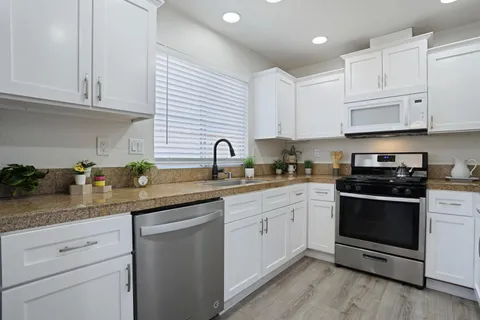 a kitchen with stainless steel appliances granite countertop a sink a stove and cabinets