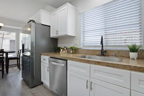a kitchen with granite countertop a sink stainless steel appliances and cabinets