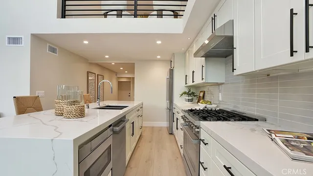 a kitchen with a sink stainless steel appliances and white cabinets