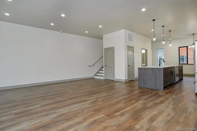 a view of a big room with wooden floor and a kitchen