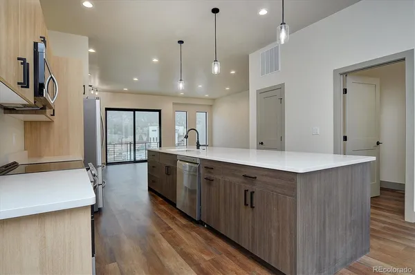 a large kitchen with stainless steel appliances kitchen island a large counter top and a wooden floors