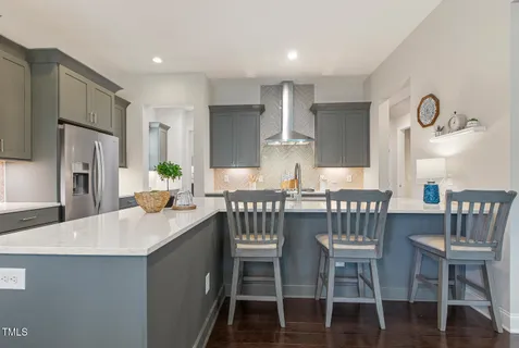 a kitchen with stainless steel appliances kitchen island granite countertop a table chairs sink and cabinets