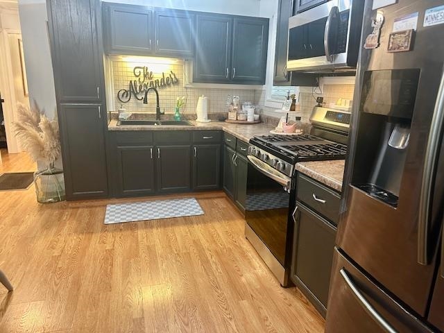 440 Angotti Road Crump, TN 38327 - Photo 5 of 30 Kitchen featuring appliances with stainless steel finishes, light hardwood / wood-style flooring, backsplash, and sink