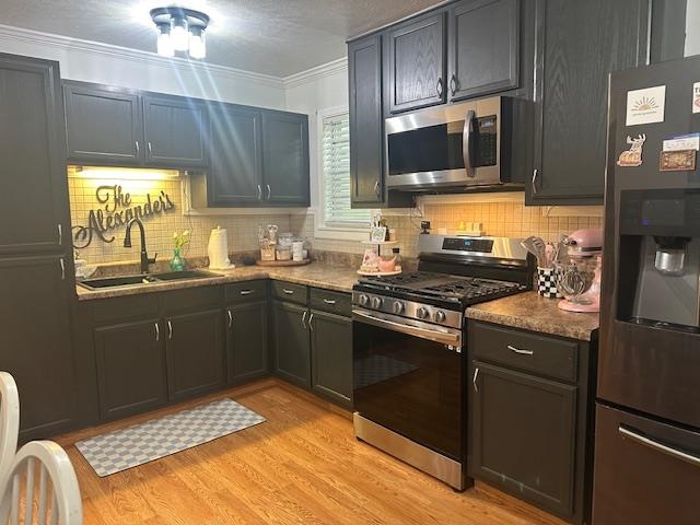 440 Angotti Road Crump, TN 38327 - Photo 6 of 30 Kitchen featuring light wood-type flooring, stainless steel appliances, decorative backsplash, sink, and ornamental molding