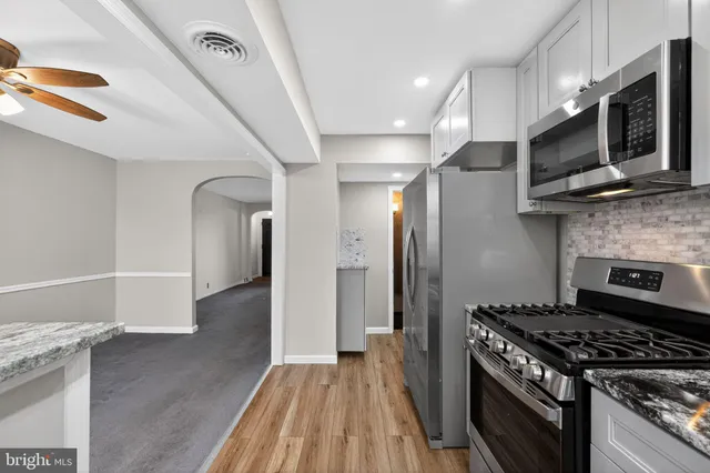 a kitchen with stainless steel appliances kitchen island granite countertop a stove and a wooden floors