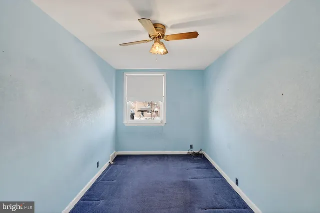 an empty room with window and ceiling fan