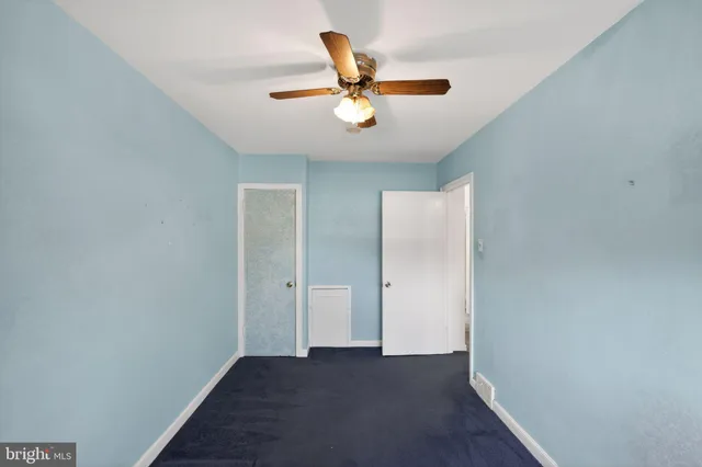 a view of an empty room with wooden floor and a ceiling fan