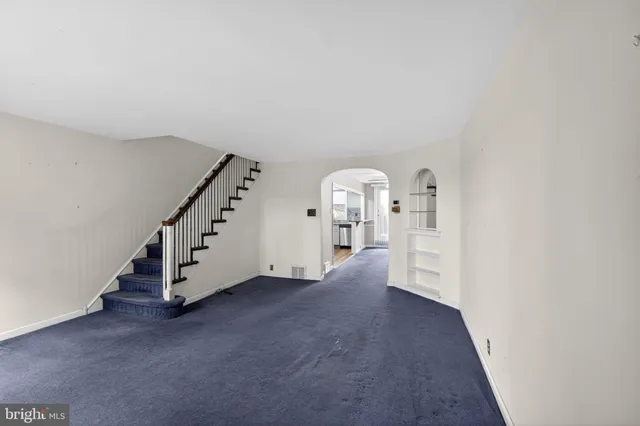 an empty room with staircase and view of hallway
