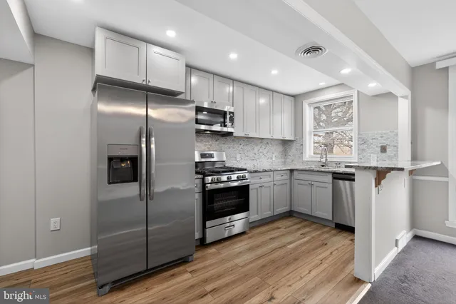 a kitchen with stainless steel appliances granite countertop a refrigerator a sink and a stove