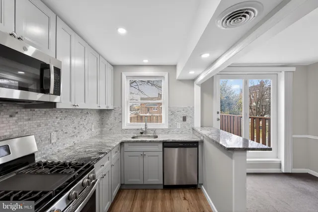 a kitchen with granite countertop a sink a stove and cabinets