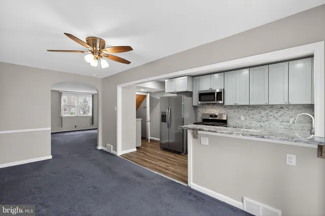 a kitchen with stainless steel appliances granite countertop a stove a sink dishwasher and a refrigerator with white cabinets