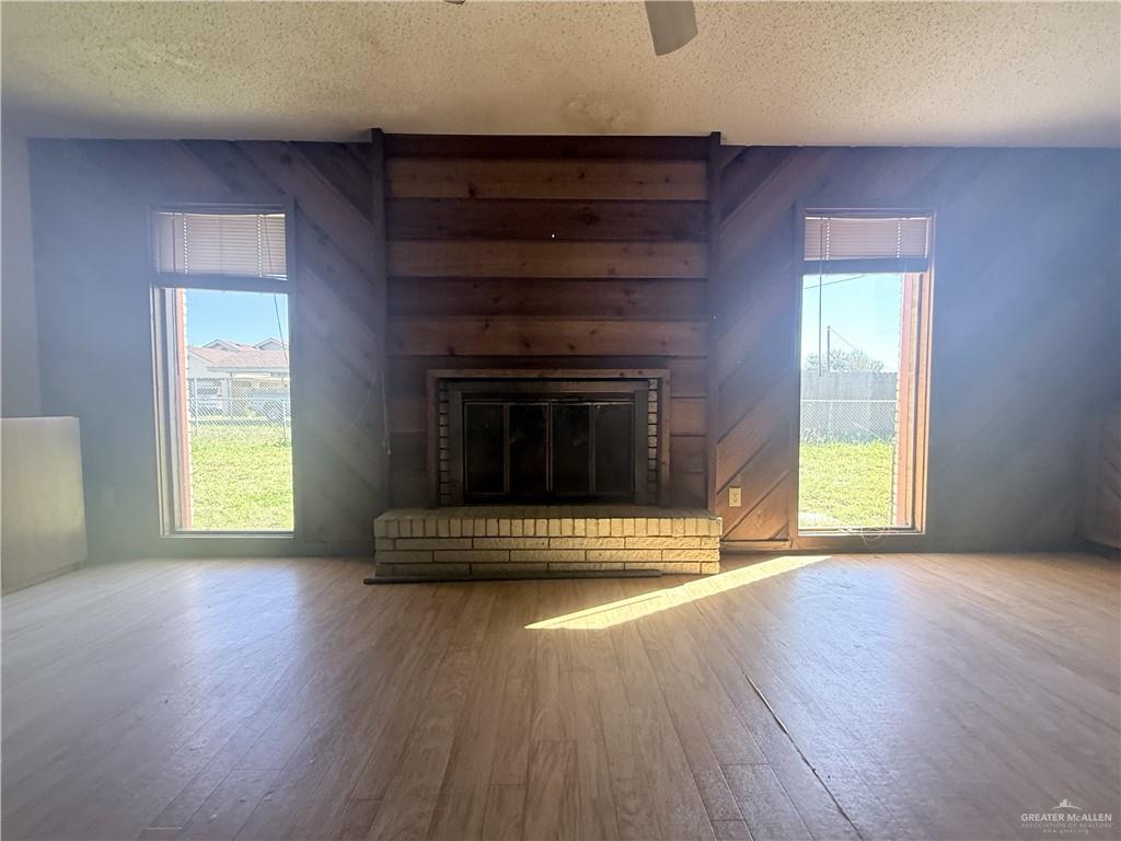 5300 East Richardson Road Edinburg, TX 78542 - Photo 3 of 12 an empty room with wooden floor a fireplace and windows