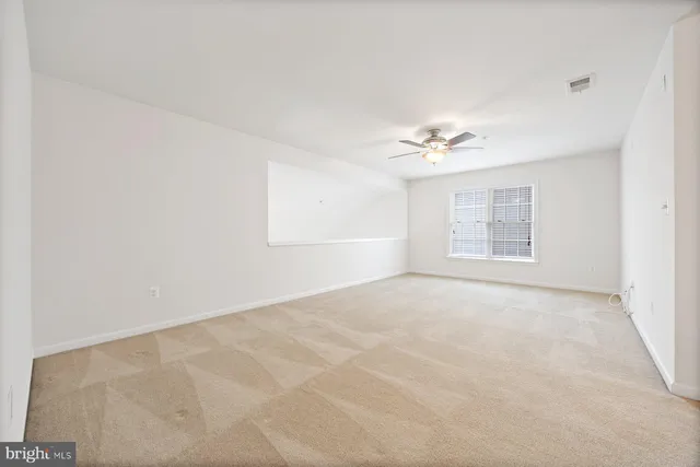 an empty room with a ceiling fan and window