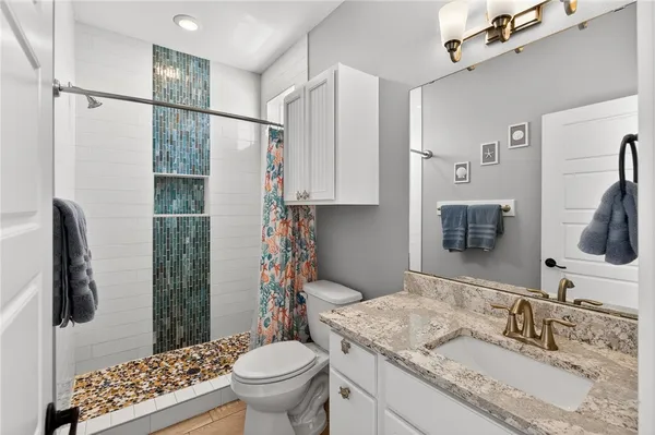 a bathroom with a granite countertop sink toilet and shower