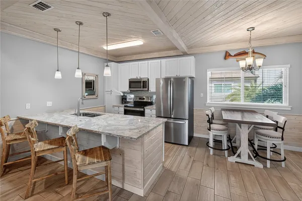 a kitchen with stainless steel appliances a dining table chairs refrigerator and sink