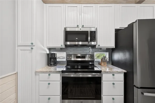 a kitchen with stainless steel appliances granite countertop a stove a refrigerator and a microwave