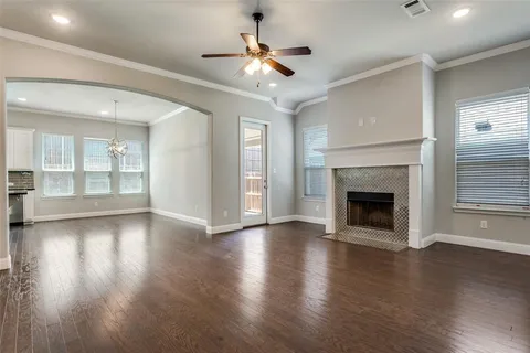 an empty room with wooden floor fireplace and windows