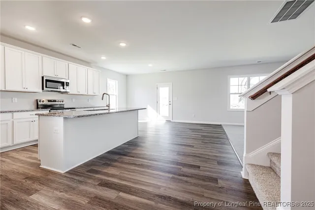 a kitchen with stainless steel appliances granite countertop a refrigerator sink and white cabinets