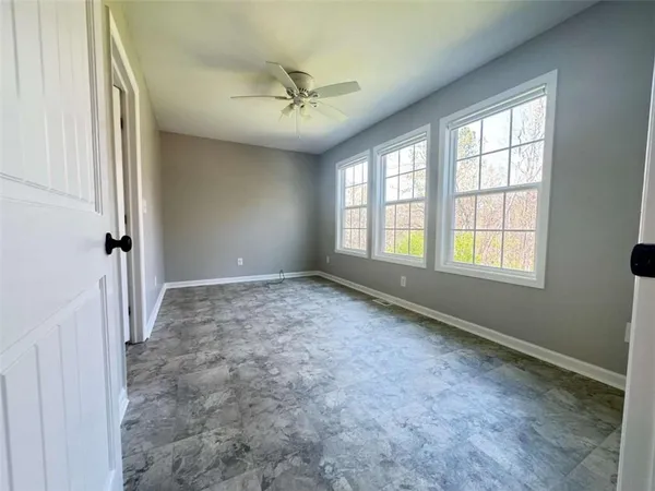 an empty room with windows and fan