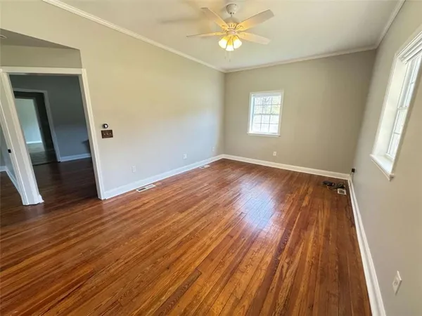 a view of an empty room with wooden floor and a window