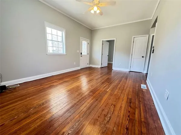 an empty room with wooden floor and windows