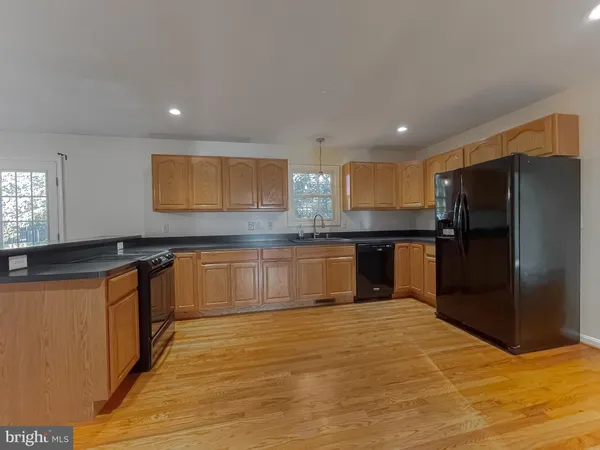 a large kitchen with stainless steel appliances granite countertop a dishwasher a stove top oven a wooden floors and a large window