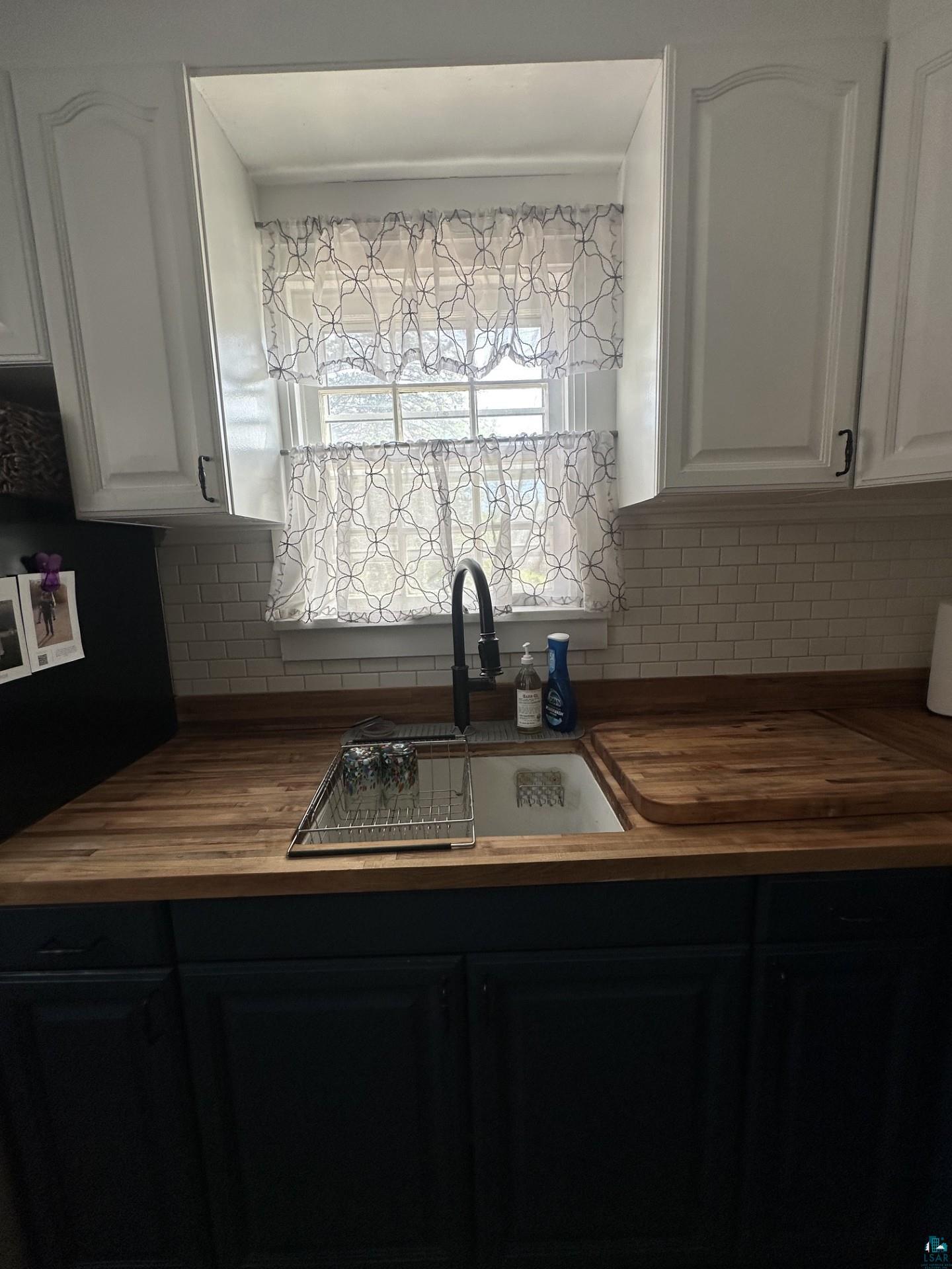 208 Chestnut Street Cloquet, MN 55720 - Photo 14 of 24 Kitchen area featuring wood-finish countertops, subway tile backsplash, and a sink with a matte black faucet