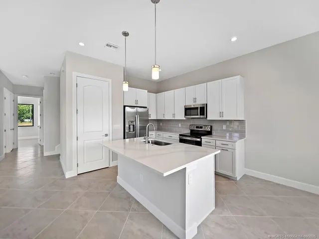 a kitchen with white cabinets and stainless steel appliances