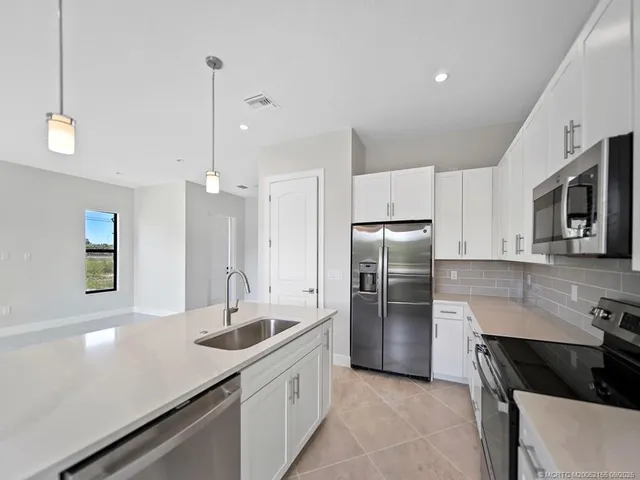 a kitchen with kitchen island a sink appliances and cabinets