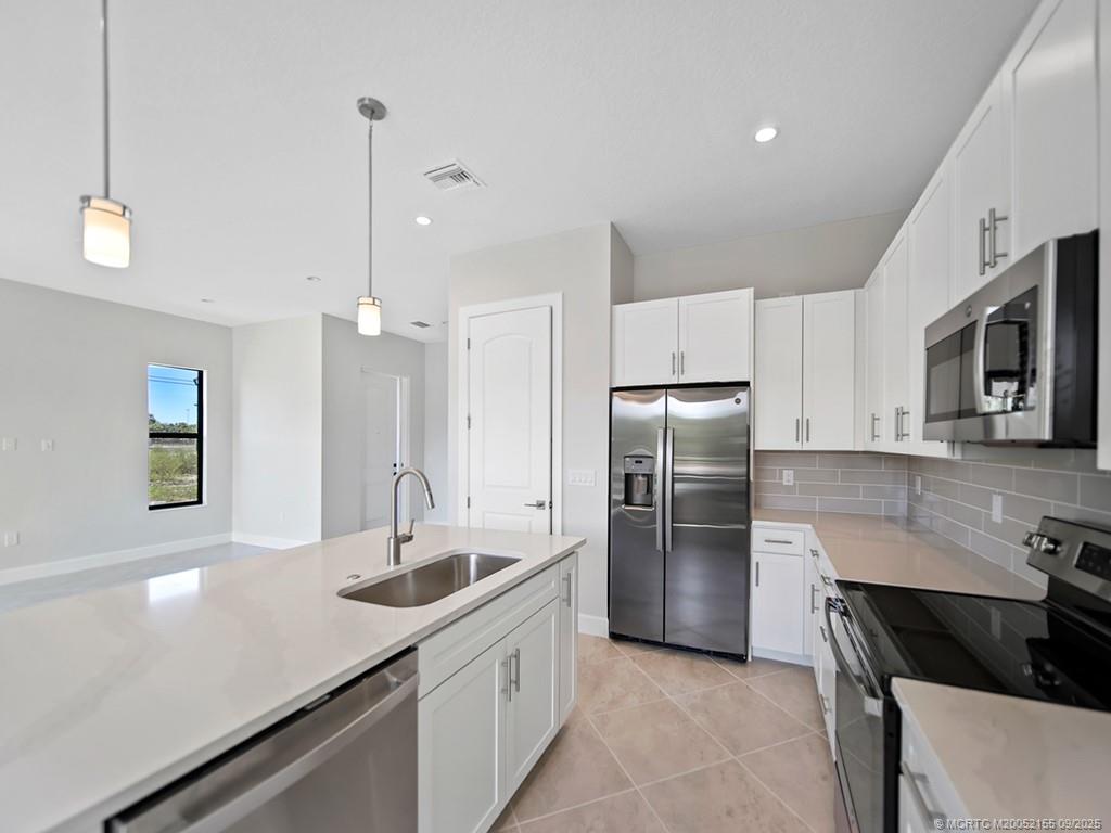 3654 Southwest Magnolia Ridge Lane Palm City, FL 34990 - Photo 9 of 23 a kitchen with kitchen island a sink appliances and cabinets