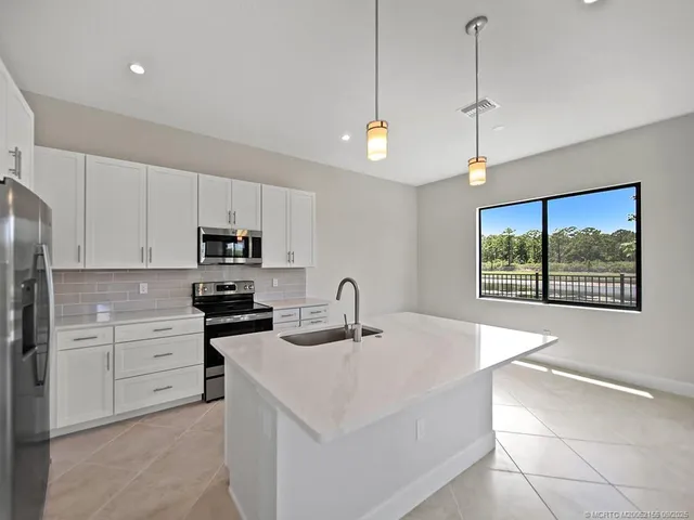 a kitchen with stainless steel appliances granite countertop a sink a stove and a refrigerator