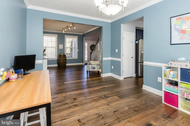 a living room with stainless steel appliances furniture wooden floor and a kitchen view