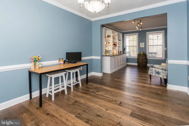 a living room with stainless steel appliances furniture a clock and a view of kitchen