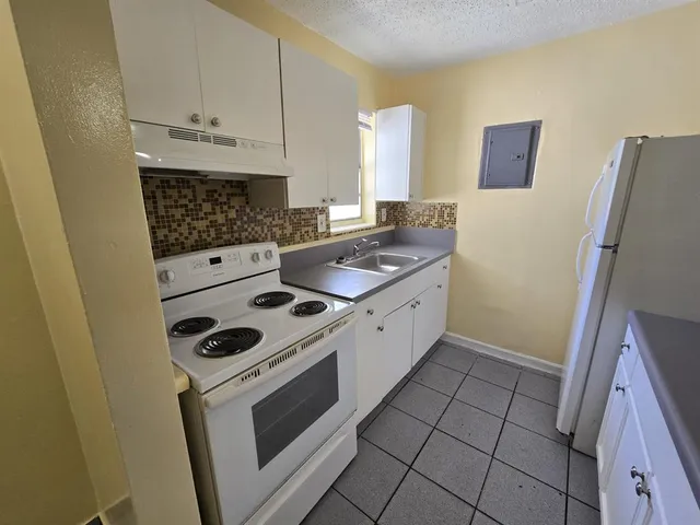 a kitchen with sink a stove a refrigerator and cabinets